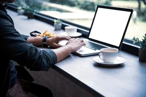 Side view of businessman using the laptop with blank white screen at coffee.. Foto stock