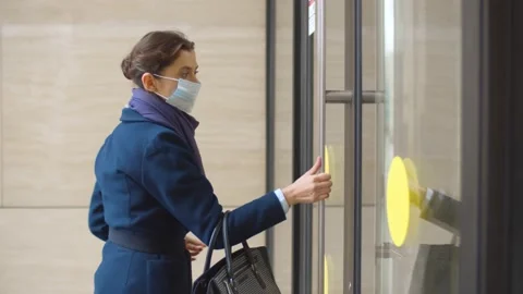Side view of businesswoman putting on safety mask and entering office building Stock Footage