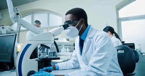 Side view of busy African American young professional male scientist medic in Stock Photos