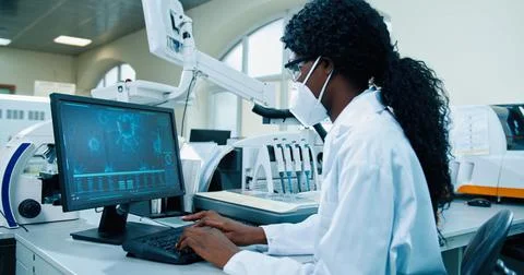 Side view of busy African American young female medical researcher sitting in Stock Photos