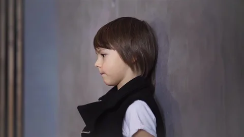 Side view of a calm cute schoolboy leaning against a gray wall Stock-Footage 90353572