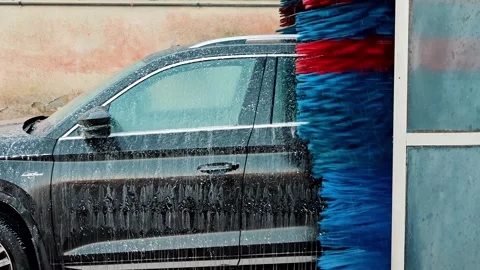 Side view of car during wash with blue and red brushes. Automated vehicle Stock Footage 324836957
