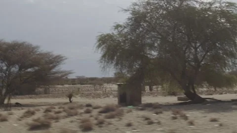 Side View in Car Moving Through Desert and a Small Village in Kenya Video stock 243686334