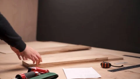 A side view of a carpenter taking two wooden boards and joining them at a right Stock Footage 103450529