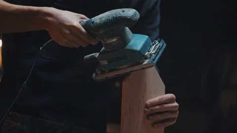 Side view of a carpenters hands with a grinder. A young apprentice guy works in Video stock 170667266