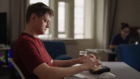 Side view of casual young man in profile working on computer, typing on split Stock Footage 348094565