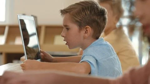 Side view of caucasian boy working on laptop while coding prompt. Pedagogy. Stockfoto's