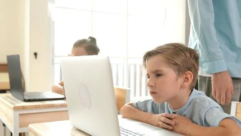 Side view of caucasian boy working on laptop while coding prompt. Pedagogy. 写真素材
