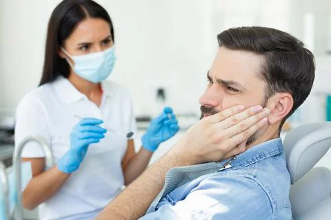 Side view of caucasian client touching face while having toothache near denti Stock Photos