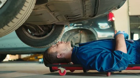 Side view of caucasian handsome auto mechanic man fastening the screws into the Stock Footage 76246369