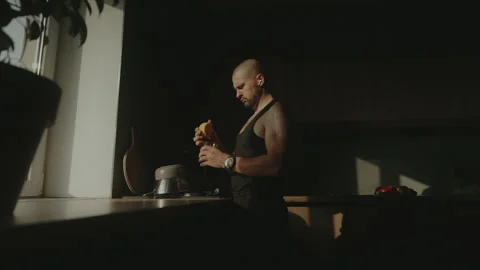 Side view of a caucasian man standing in the kitchen squeezing lemon half for Stock Footage 252734759