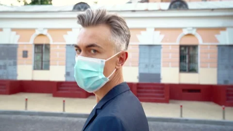 Side view on Caucasian middle-aged handsome man in medical mask walking the Stock Footage 142935480