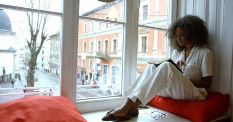 The side view of the charming afro-american woman relaxing while reading the Stock Footage 83367248