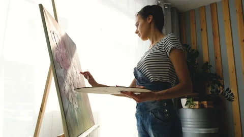Side view of charming elegant young artist paints picture Stock Footage 111033932