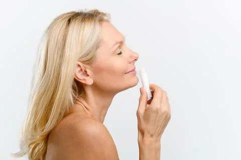 Side view at charming middle-aged woman holding hygienic lipstick Stock Photos