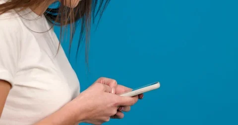 Side view of cheerful girl using smartphone with smile isolated on blue Stock Footage 124535724