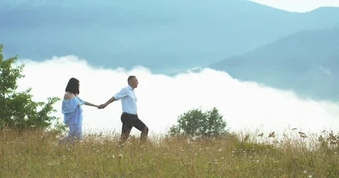 The side view of the cheerful loving couple holding hands and walking along the Stock Footage 82795242