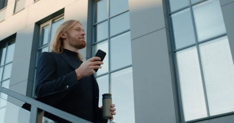 Side view of cheerful man holding thermo cup using smartphone. Bottom view of Stock-Footage 142728315