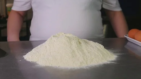 Side view chef breaks the egg with a knife and throws it into the flour Stock Footage 76087838