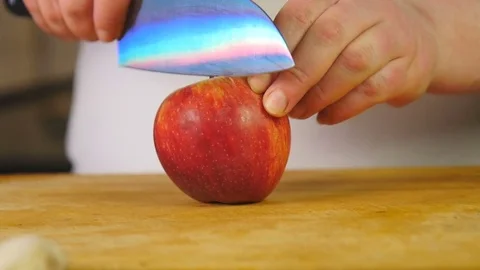 Side view chef cuts red apple into half-rings on a wooden cutting board Stock Footage 76087584