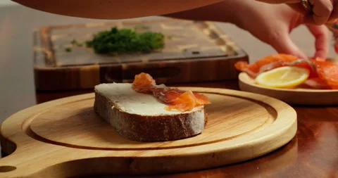 Side view Chef places slices of salted salmon on buttered bread to make an open Stock Footage 319648552
