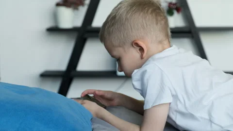Side View of A Child Boy Playing A Game on a Smartphone, Lying on A Bed Stock Footage 156244799