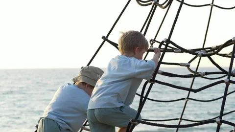 Side view of children climbing playground structure near the sea. Childhood Video stock 318294054