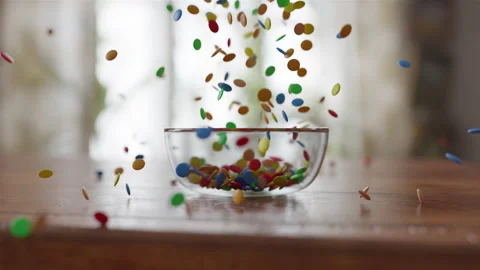 Side view of Chocolate Lentils Falling into a glass Bowl on a wooden table Stock Footage 253633873