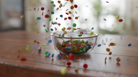 Side view of Chocolate Lentils Falling into a glass Bowl in slow motion Stock Footage 253634020
