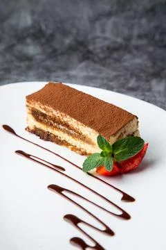 Side view of chocolate sponge cake with strawberries and mint on a white plate Stock Photos