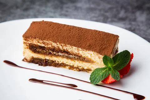 Side view of chocolate sponge cake with strawberries and mint on a white plate Stock Photos