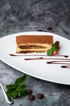 Side view of chocolate sponge cake with strawberries and mint on a white plate Stock Photos