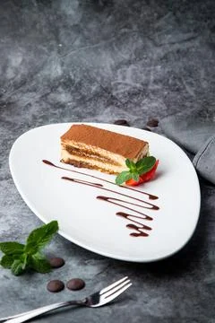 Side view of chocolate sponge cake with strawberries and mint on a white plate Stock Photos