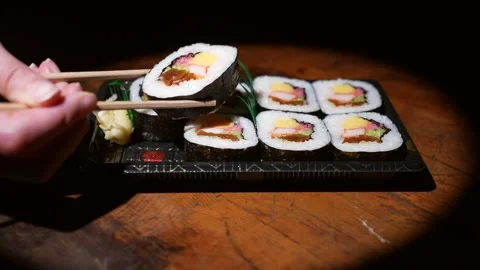 Side view of chopsticks taking sushi roll bite Stock Footage 148177197