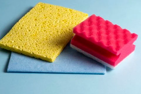 Side view of cleaning sponges of different colors and sizes laid out on a blu Stock Photos