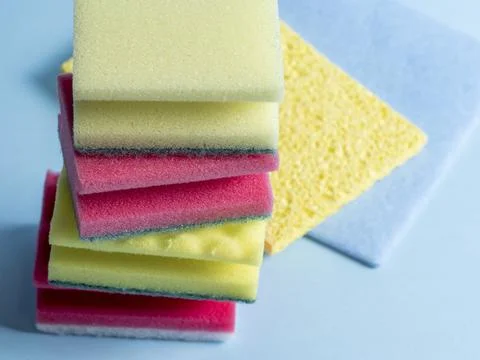 Side view of cleaning sponges of different colors and sizes laid out on a blu Foto stock
