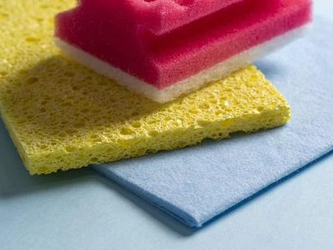 Side view of cleaning sponges of different colors and sizes laid out on a blu Stock Photos
