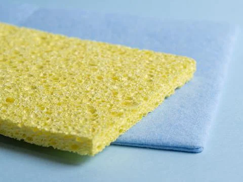 Side view of cleaning sponges of different colors and sizes laid out on a blu Stock Photos