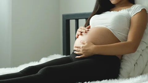 Side view close up of beautiful young woman touch her belly on white bed Stock Footage 122088228
