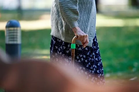 Side view close up of an elderly person's hand gripping a wooden walking cane Photos