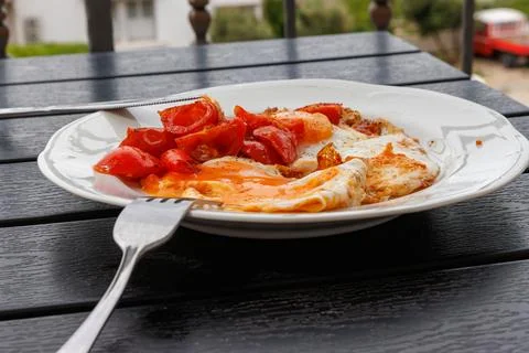 Side view close up of a fried egg served with cherry tomato on a white plat.. Stock Photos