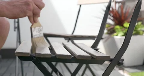 Side view close-up of a man's hand varnishing a chair on the terrace of his h Stock Footage 154636645