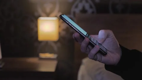 Side view. Close-up of a man's hand using a smartphone in the bedroom Stock Footage 256789727