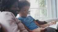 Side View Close Up Of Mixed Race Pre Teen Boy And His Father Sitting On A Sofa Stock Footage