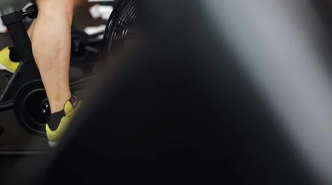 Side view close-up part of young man in sports shoes cycling at gym. slider shot Stock Footage 62446832