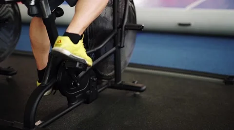 Side view close-up part of young man in sports shoes cycling at gym. slider shot Stock Footage 62446881