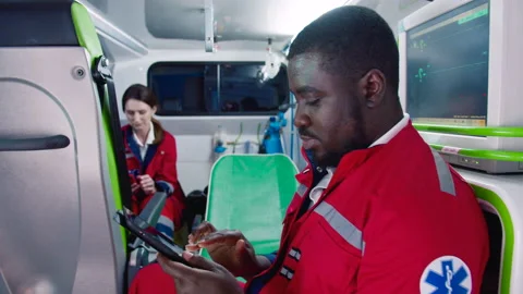 Side view close-up portrait of busy professional male paramedic sitting inside Video stock 225476024