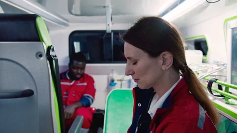 Side-view close-up portrait of tired young female paramedic sitting in ambulance Stock Footage 225473098