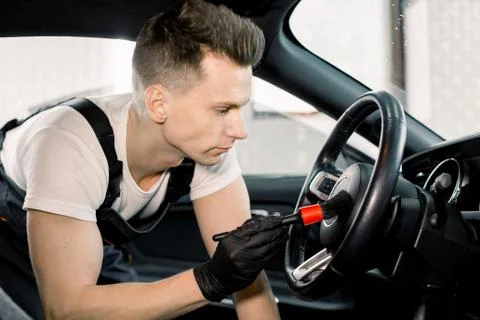 Side view close up portrait of young Caucasian male car wash detailing worker Stock Photos
