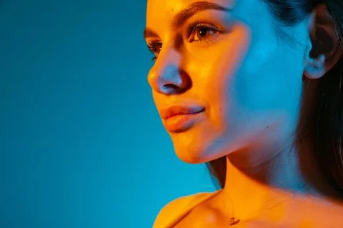 Side view close-up portrait of young bautiful girl posing isolated over blue Stock Photos